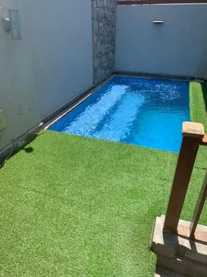 a swimming pool with green grass next to a building at One Bedroom Apartment in El Gouna Bali in Hurghada