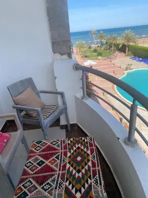 a balcony with a chair and a swimming pool at Sea View Apartment Cecelia Resort in Hurghada