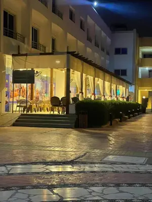 a building with a patio with tables and umbrellas at night at Sea View Apartment Cecelia Resort in Hurghada