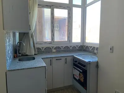 a kitchen with white cabinets and a sink and windows at Downtown Studio in Hurghada