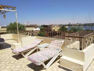 two lounge chairs and a table on a roof at Memnon Apartments in Luxor