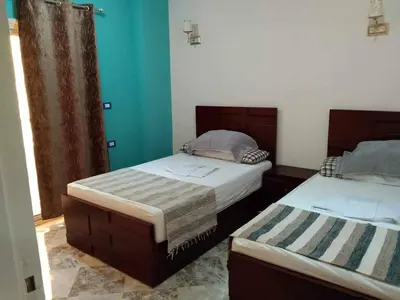 two beds in a room with blue walls at Magyipt in Hurghada