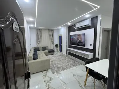 a living room with a couch and a tv on a wall at Blue Pearl 203 1BR in Hurghada