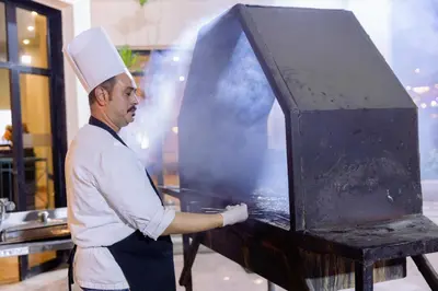 a chef standing in a kitchen preparing food at Apartment Empire Hotel in Hurghada