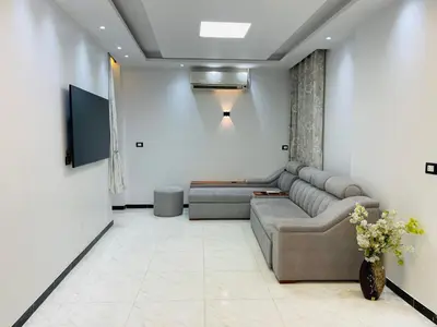 a living room with a couch and a tv at Comfortable & Modern Appartement in Luxor