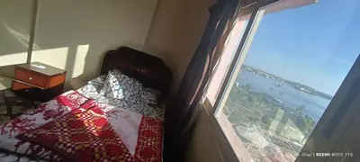 a bedroom with a bed next to a window at شقة كورنيش النيل 3غرف فيو كامل علي النيل in Aswan