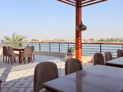 a patio with tables and chairs and a view of the water at Boutique hotel Neferu Stay in Luxor