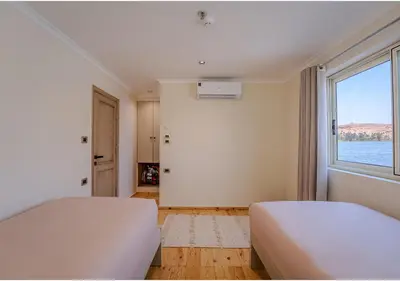 a bedroom with two beds and a large window at Anoush Dahabiya 7 nights from Luxor to Luxor each Monday in Luxor