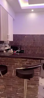 a kitchen with a black counter top with chairs at شقه للايجار غرفه وصاله ومطبخ وحمام بالهضبه الغردقه in Hurghada