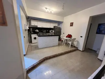 a kitchen and living room with a table and chairs at Mohamed Home in Jazīrat al ‘Awwāmīyah
