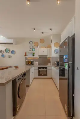 a large kitchen with a refrigerator and a dishwasher at Charming Jungle Home in Hurghada