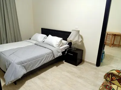 a bedroom with a bed with white sheets and a lamp at Sun and fun Hurgadah Apartments in Hurghada