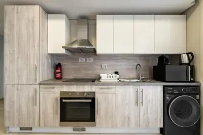 a kitchen with white cabinets and a sink and a dishwasher at Glow & Tide 1BDR w Rooftop Mangroovy Free Pool & Beach Access in Hurghada
