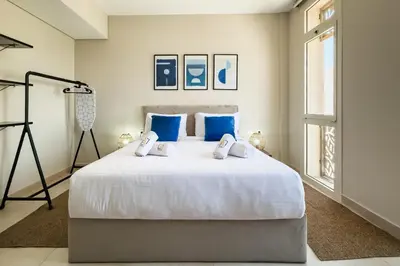 a bedroom with a large white bed with blue pillows at Glow & Tide 1BDR w Rooftop Mangroovy Free Pool & Beach Access in Hurghada