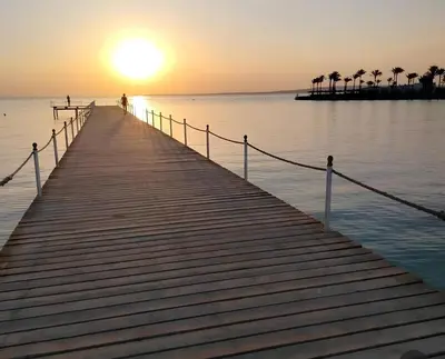 a person standing on a pier as the sun sets at Modern loft overlooking downtown in Scandic Resort in Hurghada