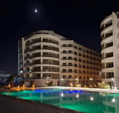 a large building with a swimming pool at night at Modern loft overlooking downtown in Scandic Resort in Hurghada