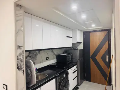 a kitchen with white cabinets and a sink and a microwave at Modern loft overlooking downtown in Scandic Resort in Hurghada