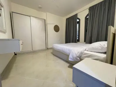 a hotel room with two beds and a cabinet at Bayt Hassan S10 - Fabulous one bedroom apartment in Hurghada