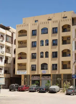 a large building with cars parked in a parking lot at Bayt Hassan S6 - Cosy 1 bedroom apartment in Hurghada