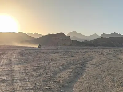 a person riding a motorcycle in the desert at sunset at Ocean Apartment in Hurghada