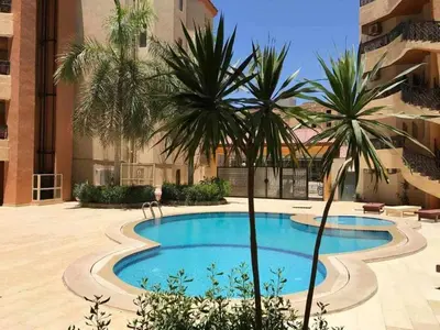 a swimming pool in the middle of a building with palm trees at Regency towers résidence in Hurghada