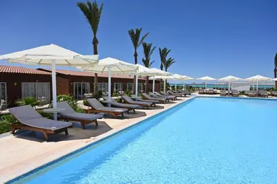 a swimming pool with lounge chairs and umbrellas at Riviera Aqua Park Resort in Hurghada
