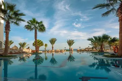 a swimming pool with palm trees and a blue sky at Salvatore Rooms All Inclusive -Cornich Street in Hurghada