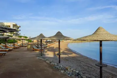 a beach with many straw umbrellas and the water at Salvatore Rooms All Inclusive -Cornich Street in Hurghada