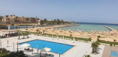 a resort with a swimming pool and a beach with umbrellas at شالية منتجع سكانديك عرابيا in Hurghada