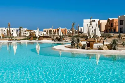 a large swimming pool in a resort with buildings at Cool & Curated 1BDR Kamaran El Gouna in Hurghada