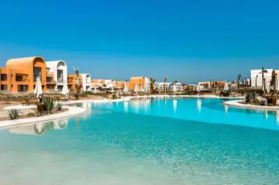 a large swimming pool in a resort with buildings at Cool & Curated 1BDR Kamaran El Gouna in Hurghada
