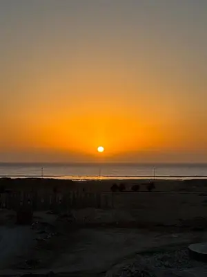 a sunset on the beach with the sun setting at DiveZen Sea View apartment in Quseir