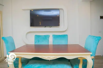 a table with blue chairs and a tv on a wall at Mirage Aqua Park Villa in Hurghada