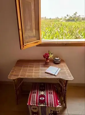a table in front of a window with a view of a field at Lady of the Sun Guesthouse in Luxor