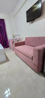 a pink couch in a living room with a flat screen tv at Tiba Golden Whire Sands Hurghada in Hurghada