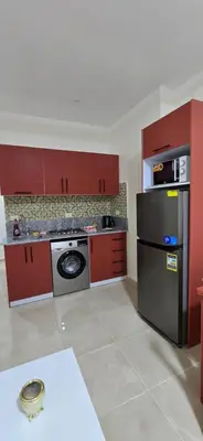 a kitchen with red cabinets and a stainless steel refrigerator at Tiba Golden Crystal Oasis Hurghada in Hurghada