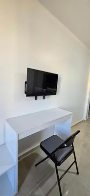 a white desk with a tv on a wall with a chair at Tiba Golden Sun and Sea Hurghada in Hurghada