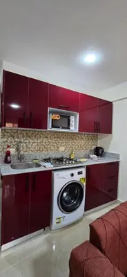 a kitchen with red cabinets and a washing machine at Tiba Golden Sea Beiss Hurghada in Hurghada