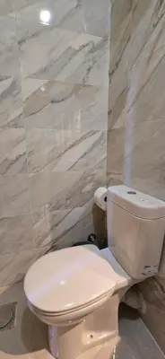 a white toilet in a bathroom with marble walls at Tiba Golden Oasis Mirage Hurghada in Hurghada