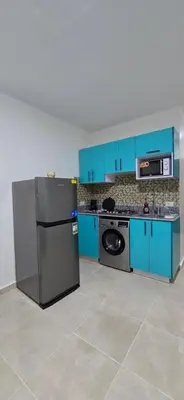 a kitchen with blue cabinets and a black refrigerator at Tiba Golden Palm Hurghada in Hurghada
