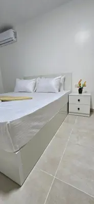 a white bed with white pillows and a night stand at Tiba Golden Sun flare Hurghada in Hurghada