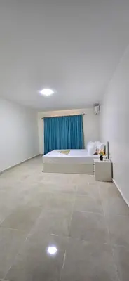 a white bedroom with a bed and a blue curtain at Tiba Golden Sun flare Hurghada in Hurghada