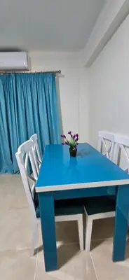a blue table with white chairs and a vase with flowers on it at Tiba Golden Sun flare Hurghada in Hurghada