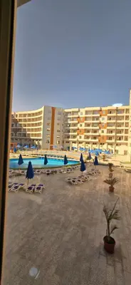 a beach with chairs and umbrellas and a pool at Tiba Golden Sunset Oasis Hurghada in Hurghada