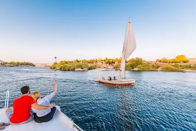 two people sitting on a boat with a sailboat at Turista Tour in Hurghada