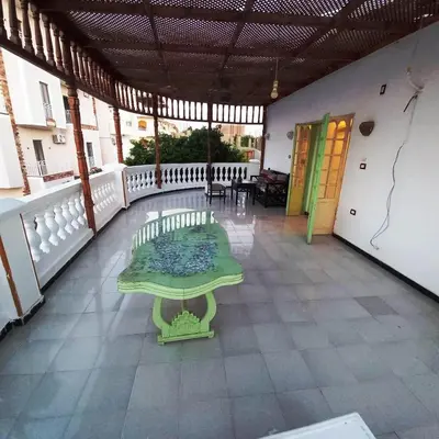 a green bench on a balcony with a table at Villa Karmen in Luxor