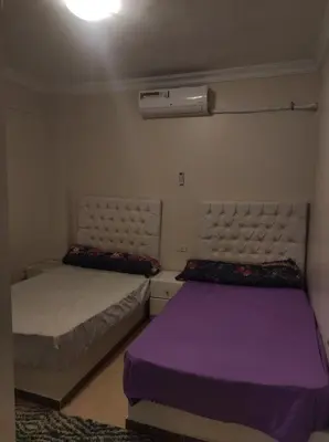 two beds in a room with purple and white at Summer land in Hurghada
