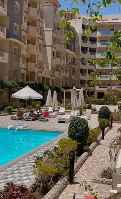 a swimming pool with chairs and umbrellas next to a building at apartment for rent in hurghada in Hurghada