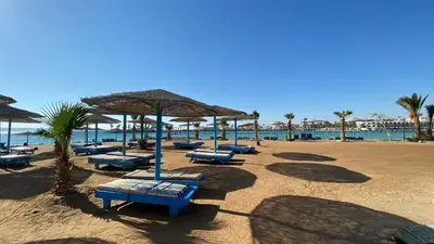 a beach with chairs and umbrellas and the ocean at TiBa Golden Resort in Hurghada
