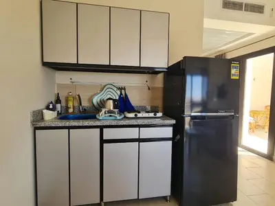 a kitchen with white cabinets and a black refrigerator at AlDau Heights Modern Studio with Terrace, Mountain & City View in Hurghada